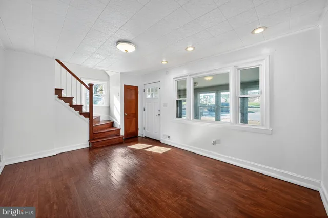 a view of an empty room with wooden floor and windows