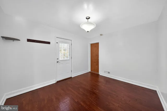 a view of an empty room with wooden floor and a ceiling fan