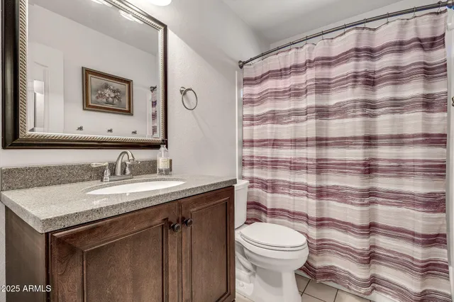 a bathroom with a granite countertop toilet sink and mirror
