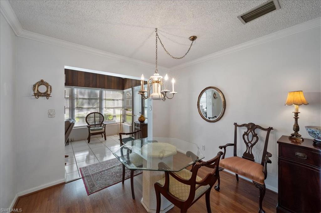 1069 Forest Lakes Drive, Unit 1B Naples, FL 34105 - Photo 11 of 29 a dining room with furniture a chandelier and a rug
