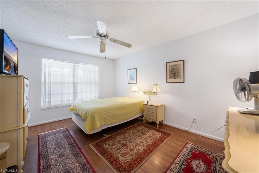 1069 Forest Lakes Drive, Unit 1B Naples, FL 34105 - Photo 20 of 29 a spacious bedroom with a bed and wooden floor