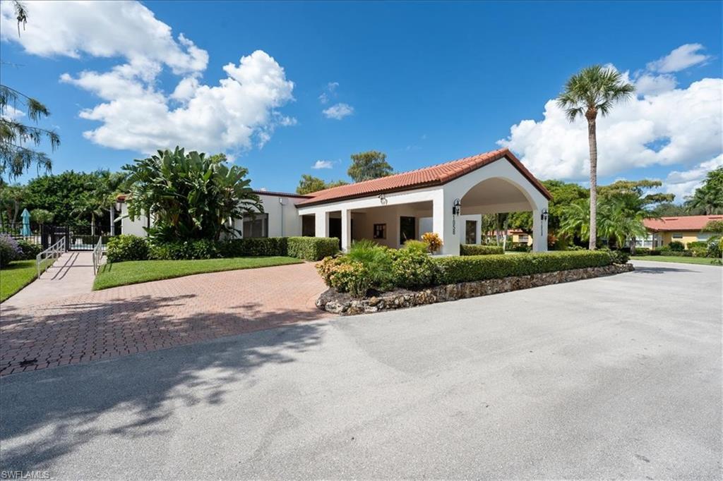 1069 Forest Lakes Drive, Unit 1B Naples, FL 34105 - Photo 29 of 29 a front view of a house with a yard and potted plants
