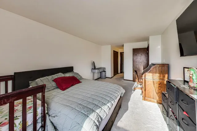 a bedroom with a bed a flat screen tv and dresser