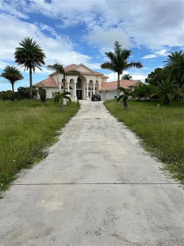 a front view of a house with a yard and potted plants