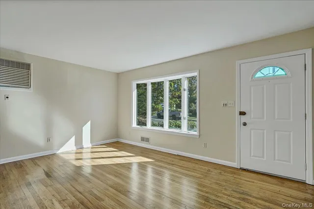 a view of empty room with window and wooden floor