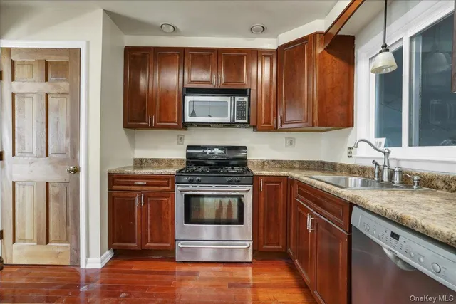 a kitchen with stainless steel appliances granite countertop a stove a sink and a microwave