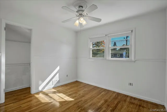 a view of an empty room with window and wooden floor