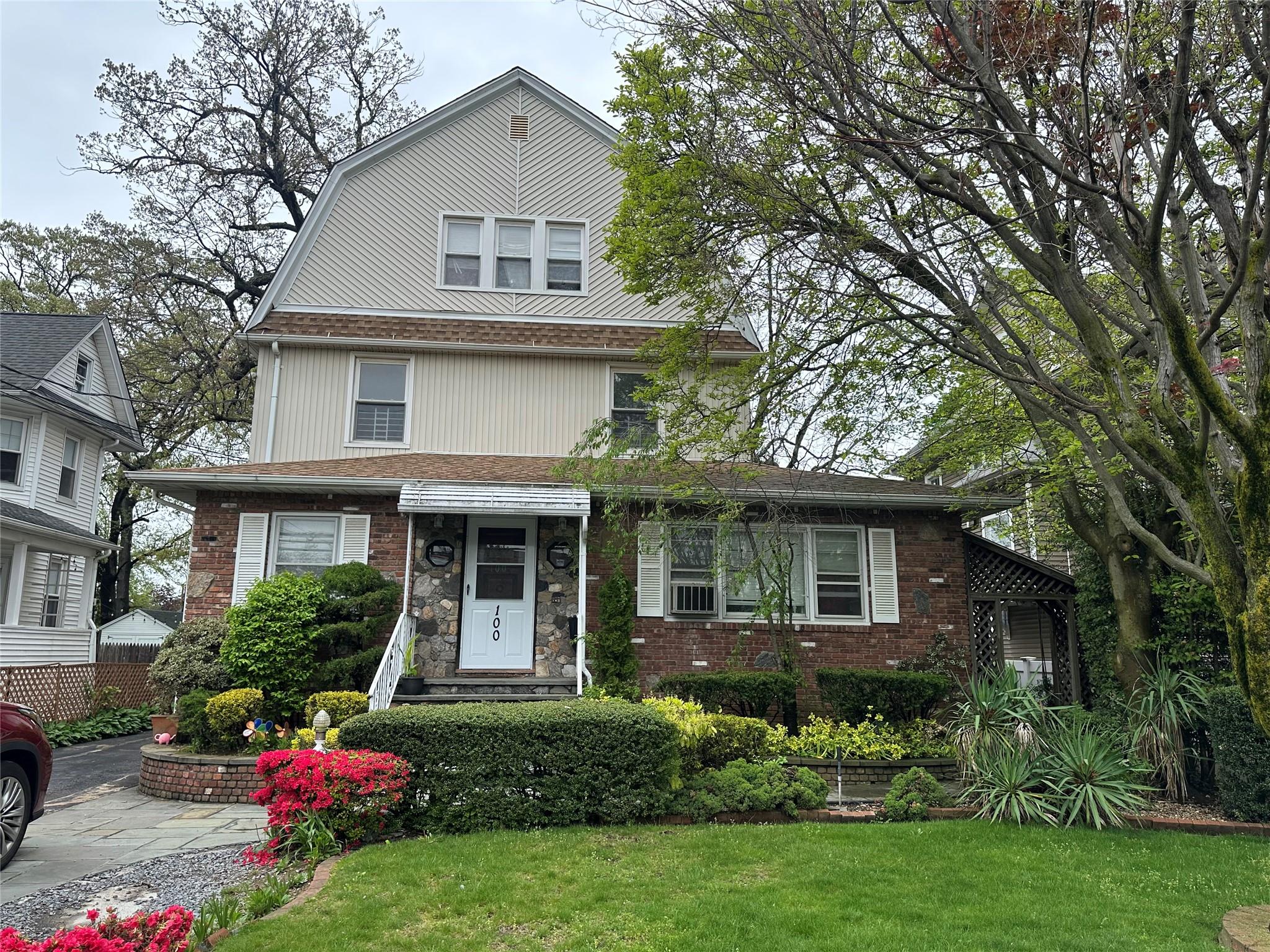 100 Earle Avenue, Unit 2 Lynbrook, NY 11563 - Photo 1 of 1 a front view of a house with a garden and trees