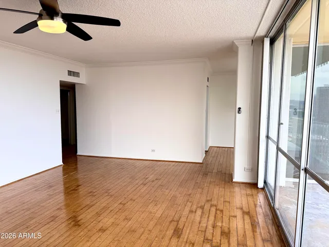 a view of an empty room with wooden floor and a window