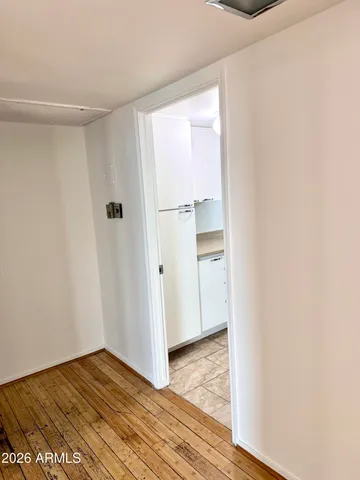 a view of an empty room with wooden floor and closet