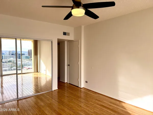 a view of an empty room with window and wooden floor