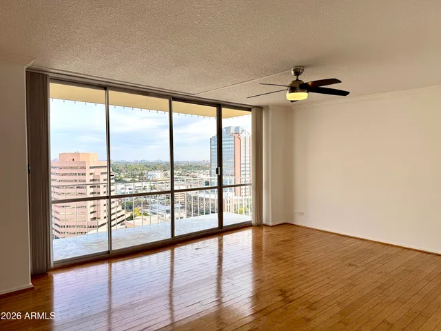 a view of an empty room with wooden floor and a window
