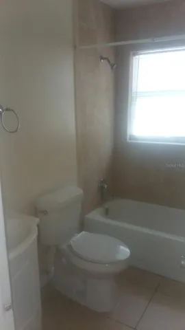 a white toilet and tub sitting next to a window