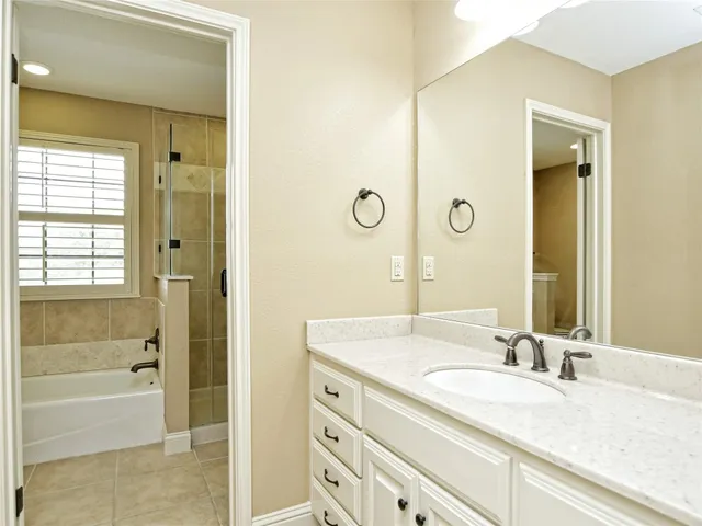 a bathroom with a granite countertop sink a mirror and a bathtub