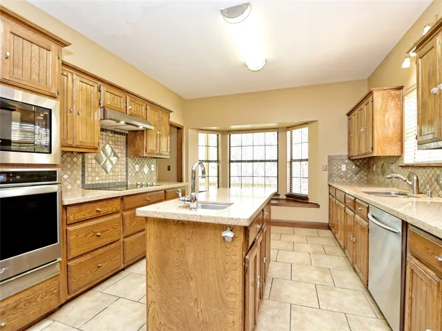 a large kitchen with kitchen island granite countertop a large window and white stainless steel appliances