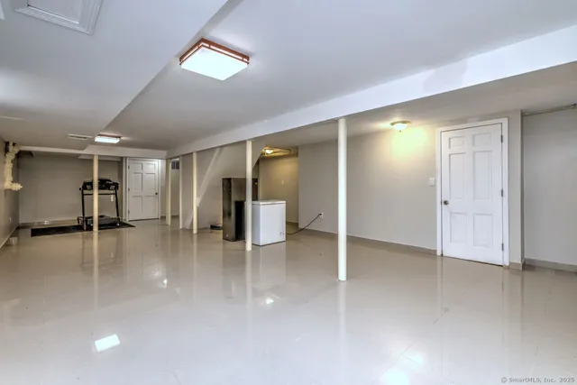 an empty room with wooden floor and way to kitchen