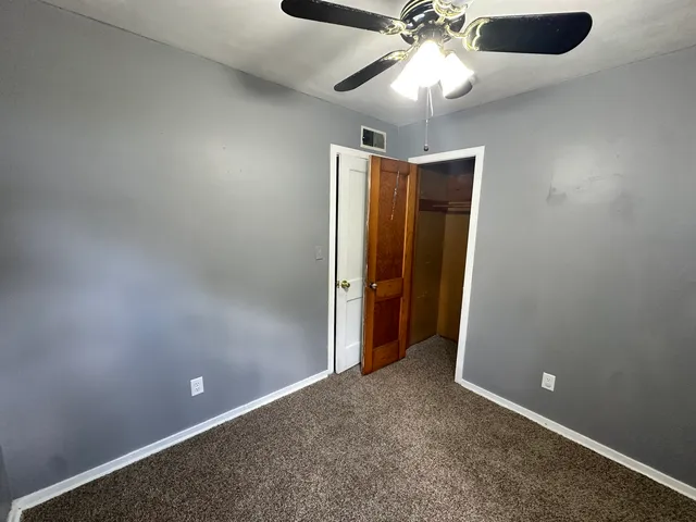 an empty room with closet and a chandelier fan