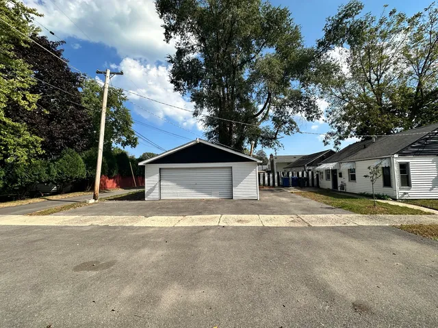 a view of the house with a yard and large trees