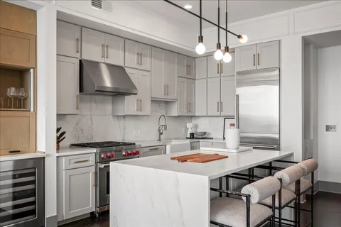 a kitchen with stainless steel appliances a stove a sink and white cabinets