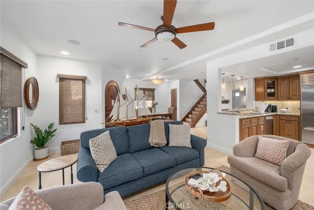 a living room with furniture kitchen view and a wooden floor