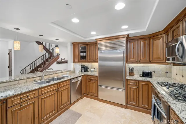 a kitchen with stainless steel appliances granite countertop a sink a stove and a refrigerator