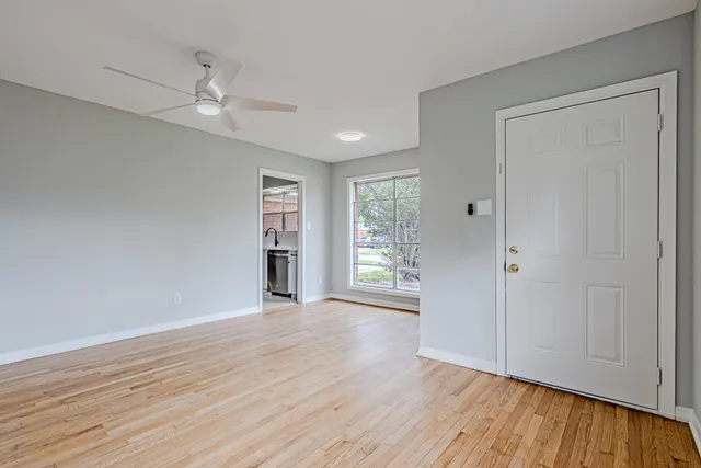 a view of an empty room with wooden floor and window
