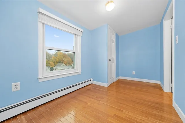 a view of an empty room with window and wooden floor