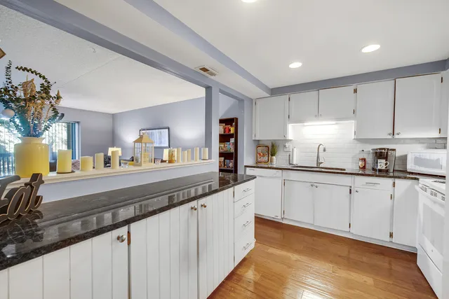 a kitchen with granite countertop white cabinets and white appliances