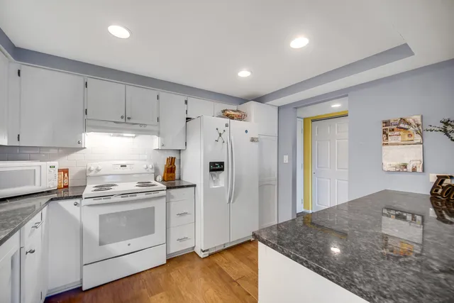 a kitchen with stainless steel appliances granite countertop a refrigerator and a stove top oven