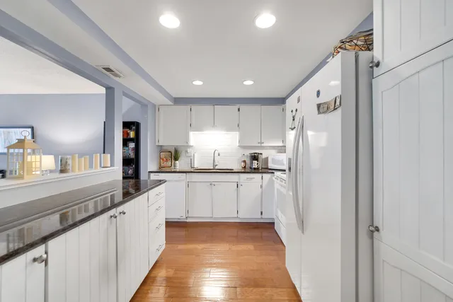 a large white kitchen with stainless steel appliances granite countertop a refrigerator and a sink