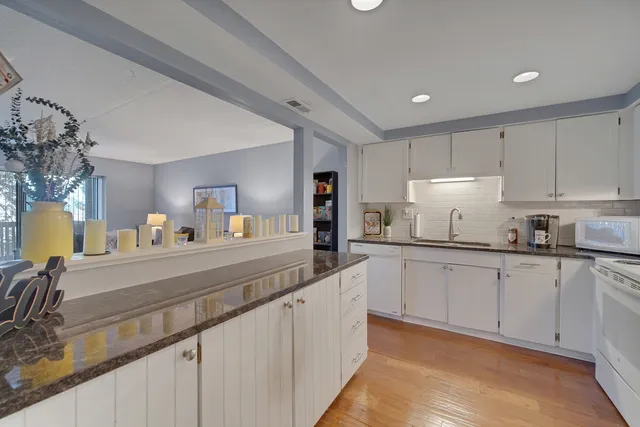 a kitchen with granite countertop white cabinets and white appliances