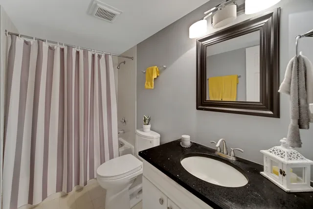 a bathroom with a granite countertop sink vanity mirror and toilet