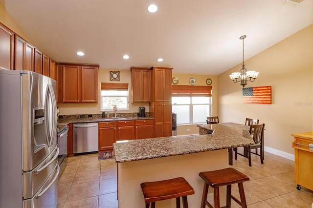 a kitchen with granite countertop kitchen island stainless steel appliances a refrigerator a stove a sink a dining table and chairs