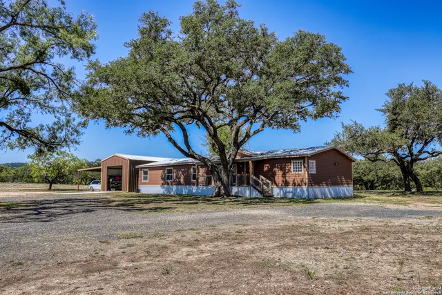 a front view of a house with large trees