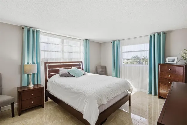 a bedroom with a bed and large windows