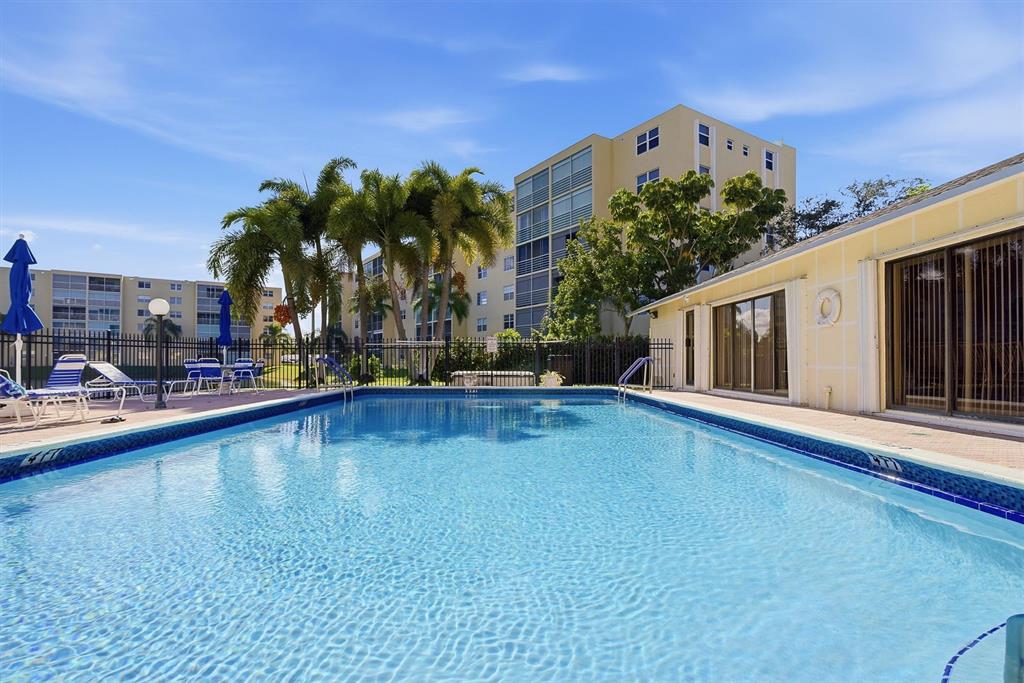 311 Southeast 3rd Street, Unit 410 Dania Beach, FL 33004 - Photo 32 of 51 a swimming pool with outdoor seating and yard