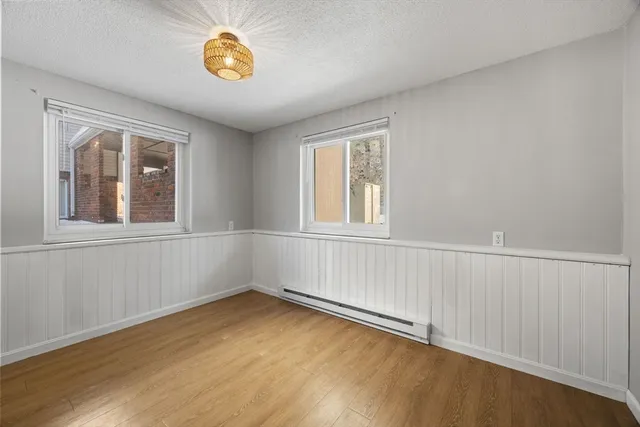 a view of an empty room with a window and wooden floor