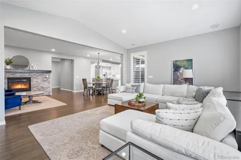 a living room with furniture a fireplace and a dining table with wooden floor