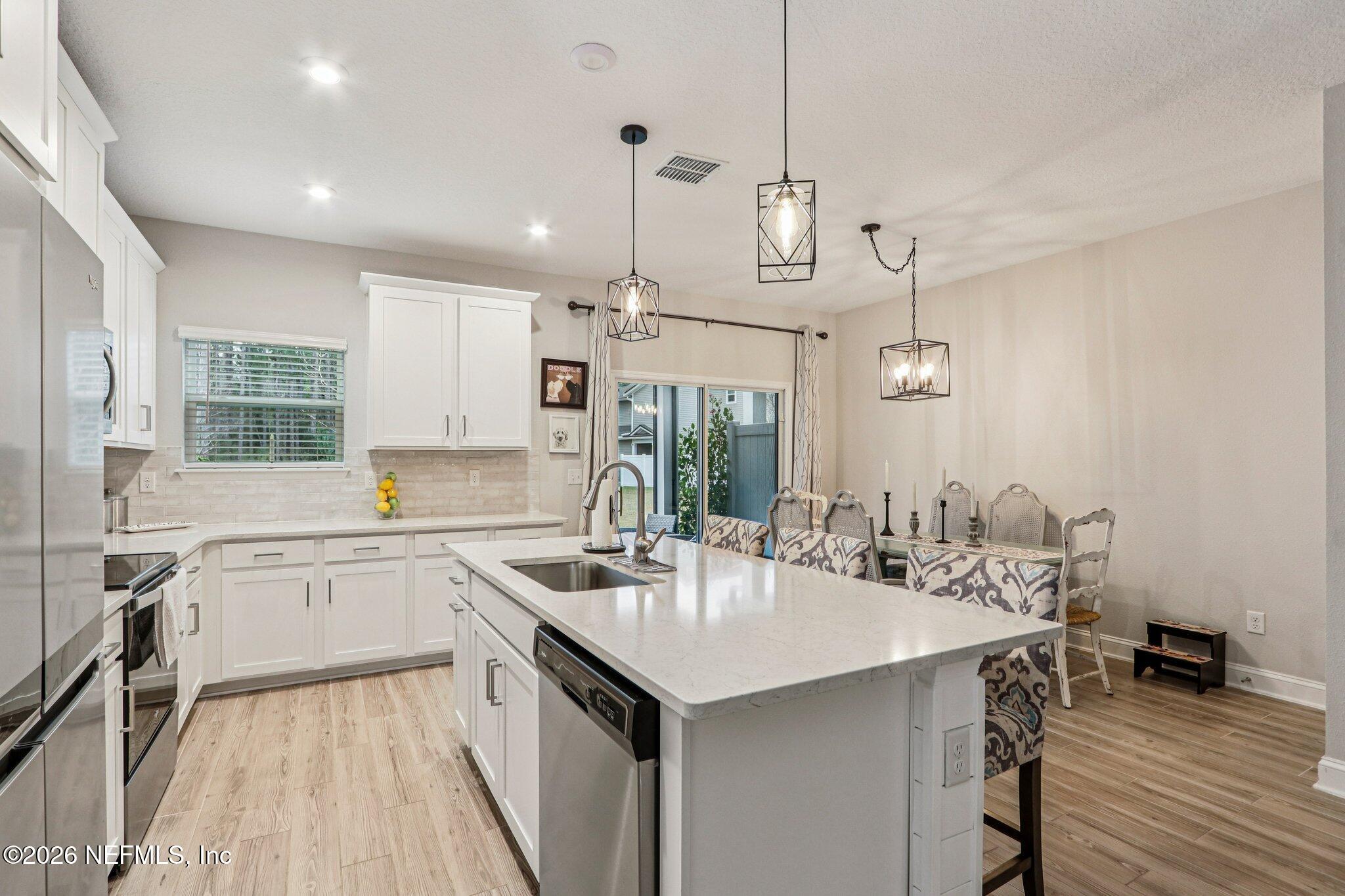 12068 Calvesta Street Jacksonville, FL 32256 - Photo 16 of 100 a kitchen with a sink a stove a dining table and chairs