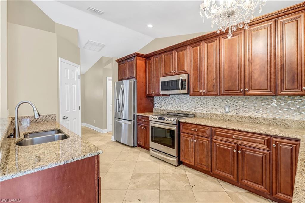 8116 Sandpiper Road Fort Myers, FL 33967 - Photo 12 of 29 Kitchen featuring a notable chandelier, sink, backsplash, and appliances with stainless steel finishes