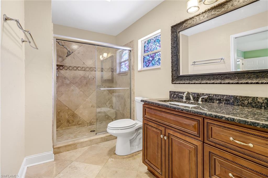 8116 Sandpiper Road Fort Myers, FL 33967 - Photo 15 of 29 Bathroom featuring tile flooring, a shower with shower door, toilet, and vanity