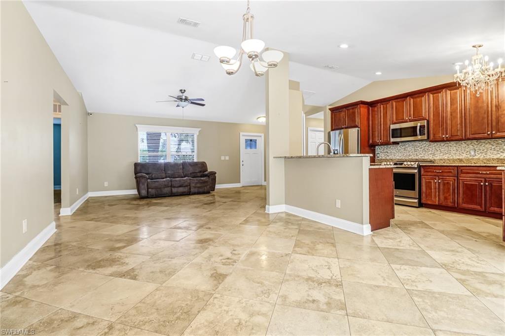 8116 Sandpiper Road Fort Myers, FL 33967 - Photo 7 of 29 Kitchen with light tile floors, tasteful backsplash, ceiling fan with notable chandelier, and stainless steel appliances