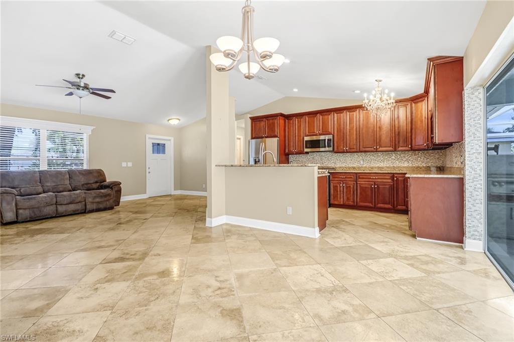 8116 Sandpiper Road Fort Myers, FL 33967 - Photo 8 of 29 Kitchen with ceiling fan with notable chandelier, appliances with stainless steel finishes, decorative light fixtures, backsplash, and light tile flooring