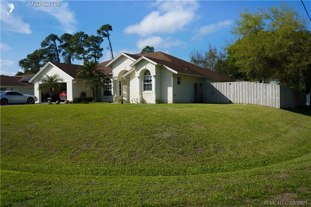 7302 Santa Rosa Parkway Fort Pierce, FL 34951 - Photo 3 of 33 a white house with a small yard and big trees