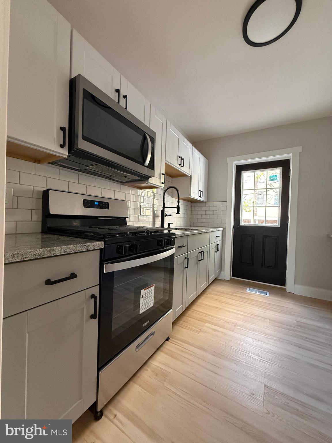 1263 South Merrimac Road Camden, NJ 08104 - Photo 7 of 16 a kitchen with stainless steel appliances granite countertop a stove a sink and a microwave