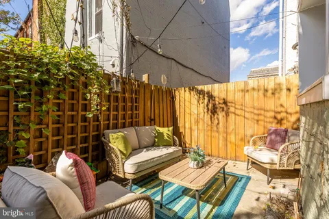 a view of a patio with couches and table and chairs with wooden floor and fence