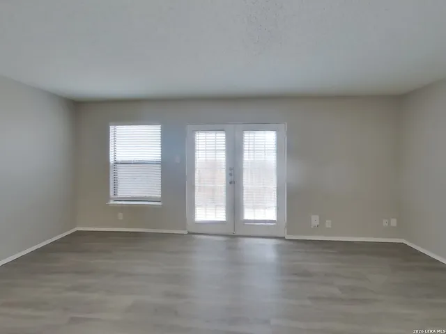 a view of an empty room with wooden floor and window