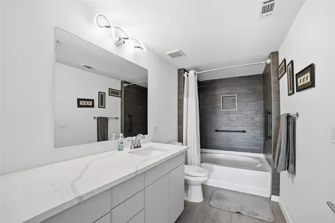 a bathroom with a granite countertop sink a toilet and bathtub