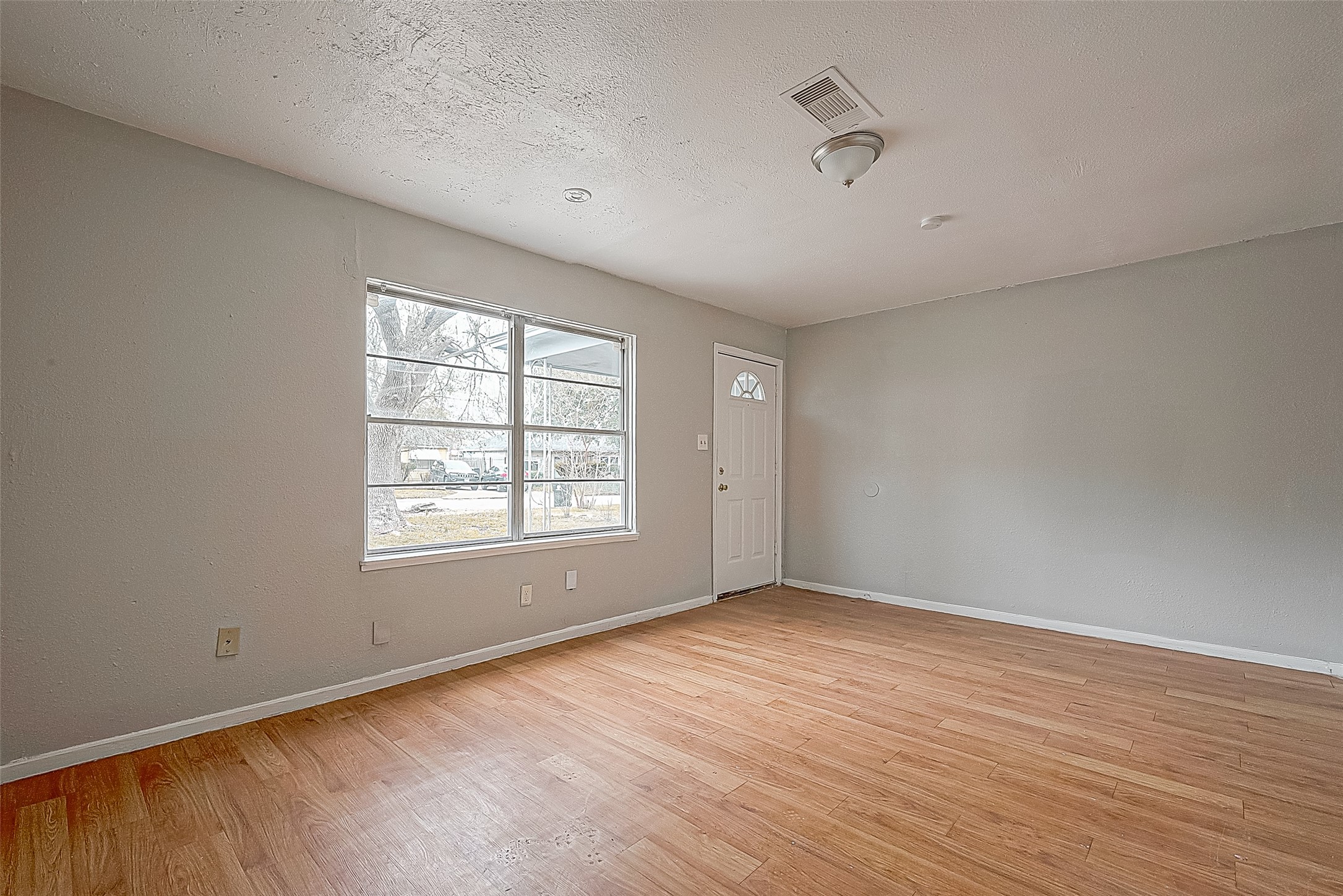 4910 Paradise Lane Houston, TX 77048 - Photo 3 of 15 an empty room with wooden floor and windows