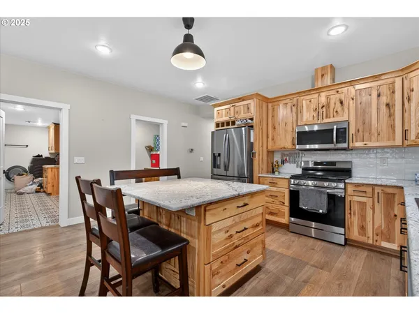 a kitchen with stainless steel appliances granite countertop a stove a sink dishwasher and a microwave with wooden floor